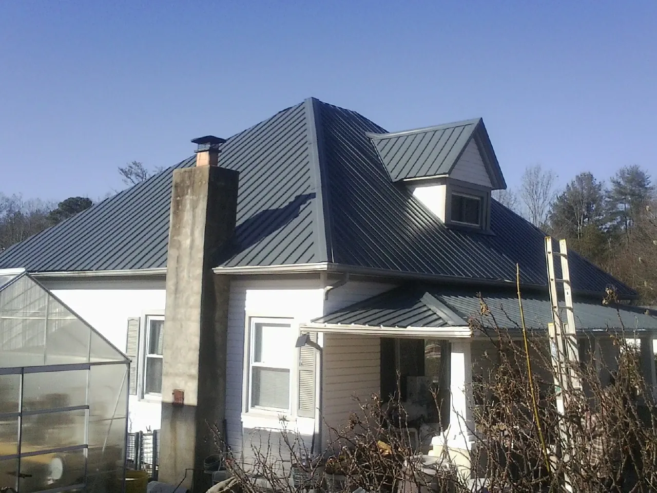 Dark blue standing seam metal roof on a white farmhouse with dormer — Slate & Tile Roof Repair by Roofing Brothers in Yantic