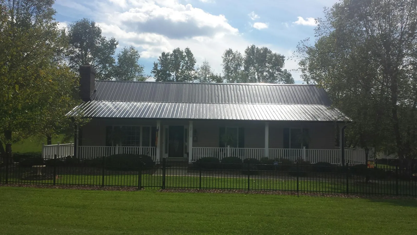 Gray metal roof on a brick ranch with a full width front porch — Gutter Guard Installation work by our crew in Yantic