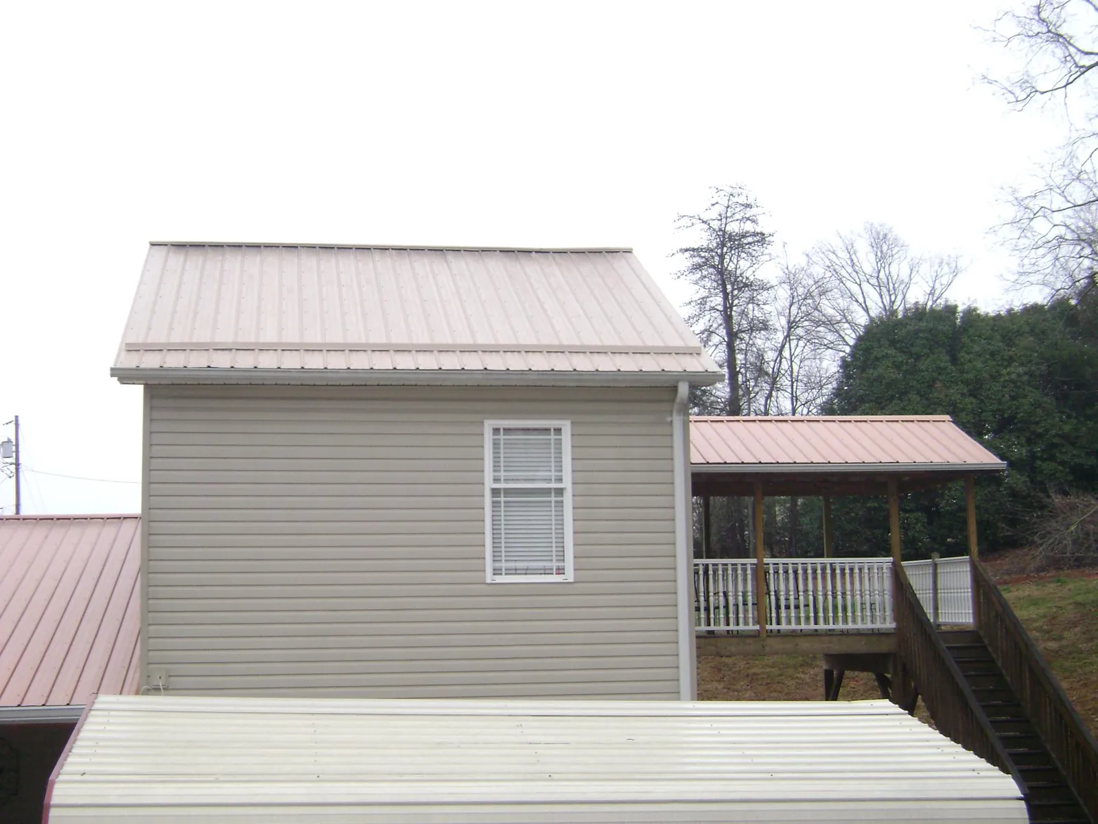 Tan metal roofs on a two story addition and attached porch, from a Roof Replacement job in Yantic