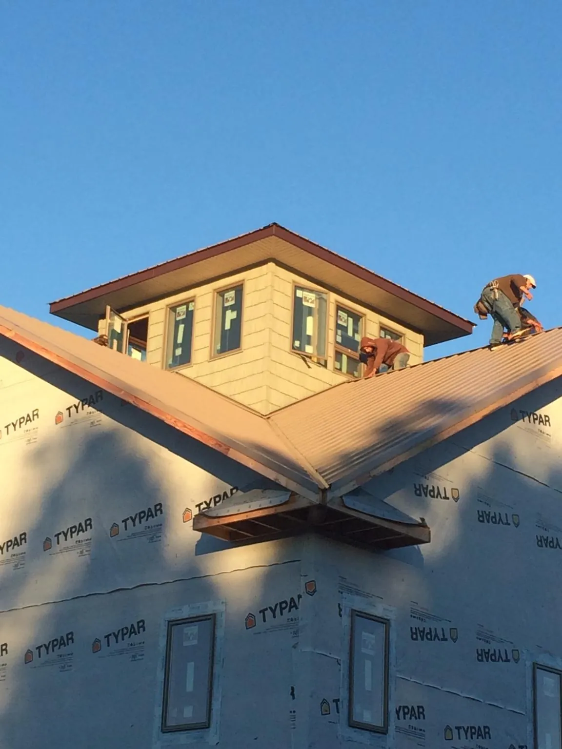 Roofers working around a rooftop cupola on a new metal roof at sunset — Roof Waterproofing in Yantic by Roofing Brothers